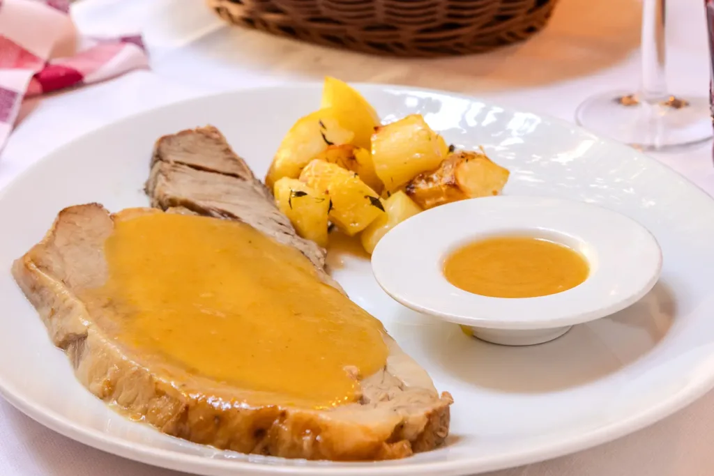 Punta di vitello farcita al forno, servita con salsa e verdure in trattoria tradizionale di Parma